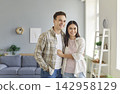 Portrait of young happy smiling couple standing in the living room at home together and hugging. 142958129