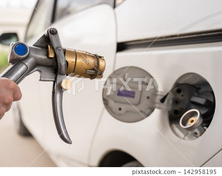 A woman fills a car with gas. Close-up of her hands. A woman fills a car with gas. Close-up of her hands. 142958195