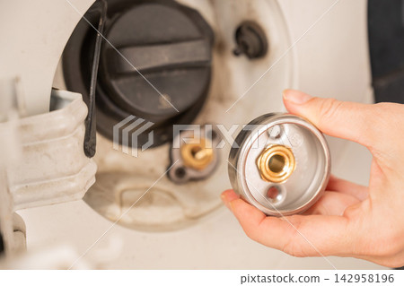 A woman installs an adapter on a gas tank in a car. A woman installs an adapter on a gas tank in a car. 142958196