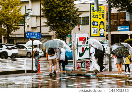 A rainy intersection as seen from a convenience store parking lot. A rainy intersection as seen from a convenience store parking lot. 142958283