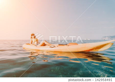 Kayaking Woman Ocean Water - Woman sits in a kayak on a calm ocean. Kayaking Woman Ocean Water - Woman sits in a kayak on a calm ocean. 142958491