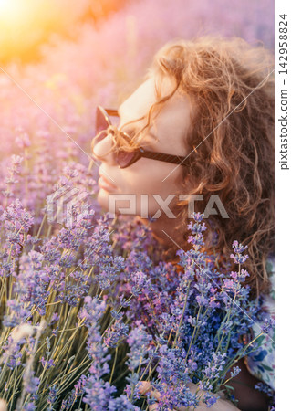 Lavender, woman, flowers, curly haired woman enjoying the scent of lavender blossoms in a sunlit field during a warm summer afternoon Lavender, woman, flowers, curly haired woman enjoying the scent of lavender blossoms in a sunlit field during a warm summer afternoon 142958824