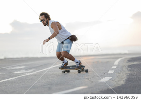 Skateboarding on the street near the beach during the late afternoon Skateboarding on the street near the beach during the late afternoon 142960059
