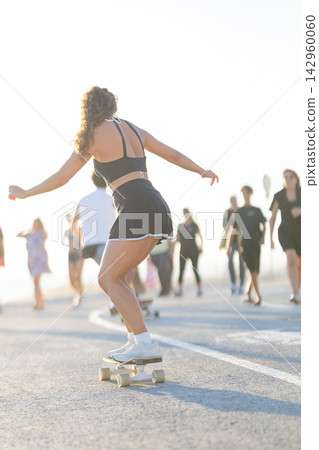 Skateboarding on a sunny day at the beach with people walking nearby Skateboarding on a sunny day at the beach with people walking nearby 142960060