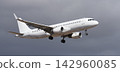 The plane lands, passenger airliner. The plane lands. A white plane flies in storm clouds, preparing to land at the airport 142960085