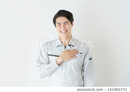 Portrait of a young Japanese man in work clothes against a white background. Portrait of a young Japanese man in work clothes against a white background. 142960733