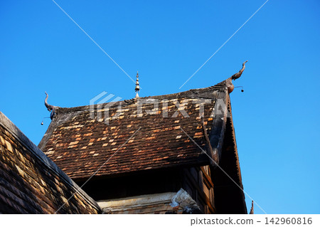 Close up detail of ancient roof architecture lanna temple with blue sky of Chiang Mai in Thailand. 142960816