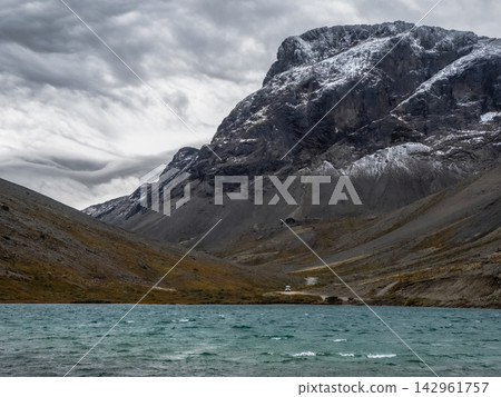 Scenic autumn landscape of Khibiny mountains with turquoise lake and snow-dusted rocky peaks under dramatic stormy sky, Kola Peninsula, Russian Arctic. 142961757