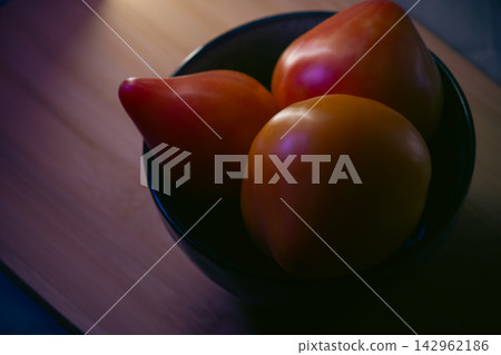 Fresh ripe oxheart tomatoes in a ceramic bowl on wooden board 142962186