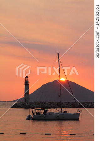 Seascape at sunshine. Lighthouse and sailings on the coast. Seaside town of Turgutreis Seascape at sunshine. Lighthouse and sailings on the coast. Seaside town of Turgutreis 142962651
