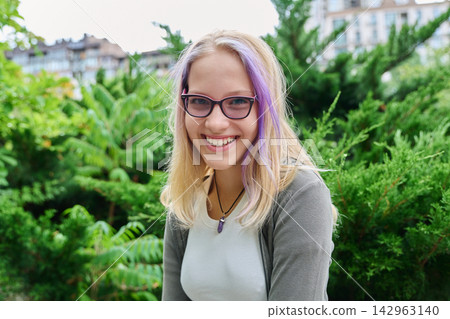 Smiling teenage girl wearing glasses looking at camera outdoors portrait Smiling teenage girl wearing glasses looking at camera outdoors portrait 142963140