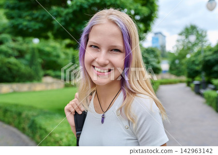 Smiling teenage student portrait with purple hair strands outdoors in city park Smiling teenage student portrait with purple hair strands outdoors in city park 142963142