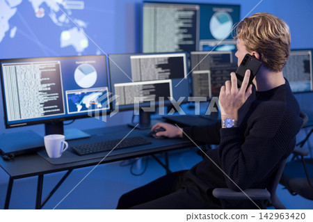 Cybersecurity analyst monitoring reports in a secure control room 142963420