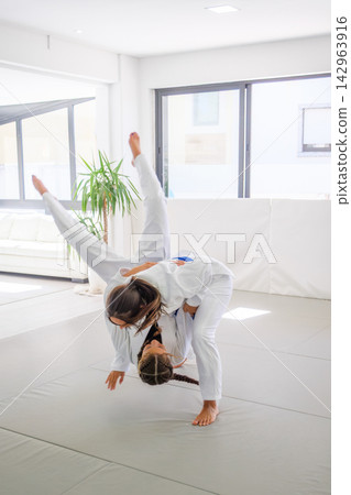Women practice a hip throw during jiu jitsu training in a dojo Women practice a hip throw during jiu jitsu training in a dojo 142963916