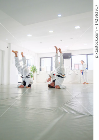 Jiu jitsu students holding headstands during a warm up Jiu jitsu students holding headstands during a warm up 142963917