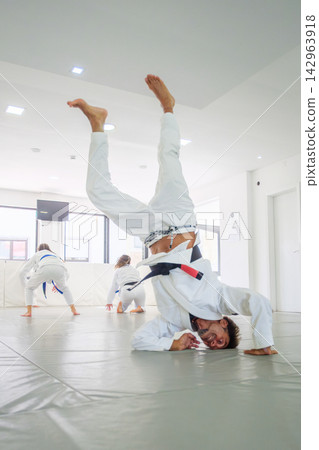 Jiu jitsu black belt balancing in a supported headstand Jiu jitsu black belt balancing in a supported headstand 142963918