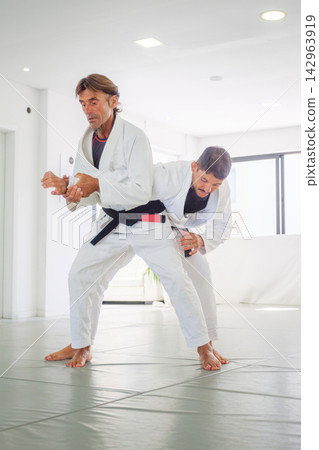 Jiu jitsu instructor demonstrating a standing armpit lock Jiu jitsu instructor demonstrating a standing armpit lock 142963919