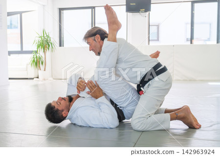 Jiu jitsu instructor demonstrating an armbar setup from guard Jiu jitsu instructor demonstrating an armbar setup from guard 142963924