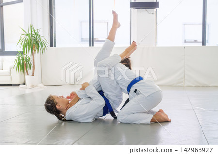 Jiu jitsu students entering arm control from open guard 142963927