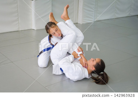 Jiu jitsu students practicing a juji gatame arm bar setup Jiu jitsu students practicing a juji gatame arm bar setup 142963928