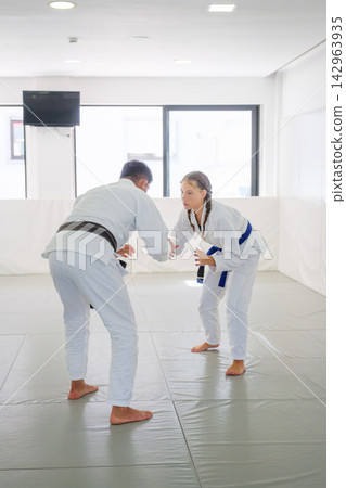Instructor and student sparring in a jiu jitsu dojo Instructor and student sparring in a jiu jitsu dojo 142963935