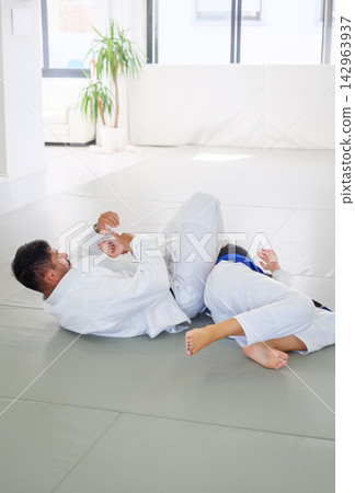 Jiu jitsu instructor and student practicing an armbar Jiu jitsu instructor and student practicing an armbar 142963937