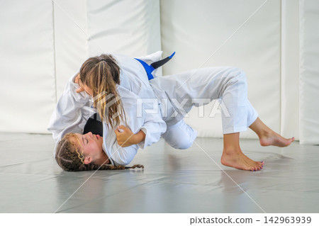 Students practicing a Brazilian jiu jitsu pin in a dojo 142963939
