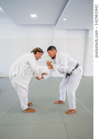 Men practicing jiu jitsu grip fighting in a martial arts dojo Men practicing jiu jitsu grip fighting in a martial arts dojo 142963942