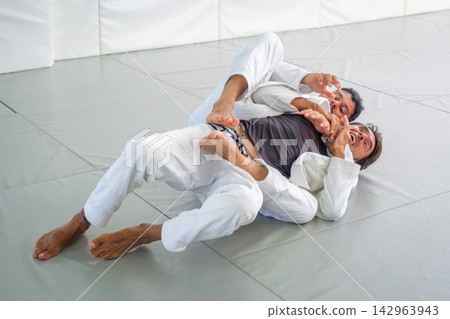 Jiu jitsu partners demonstrating rear choke defense Jiu jitsu partners demonstrating rear choke defense 142963943