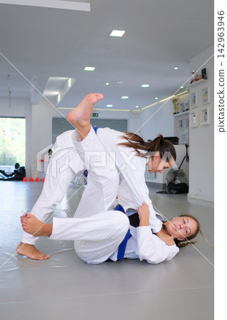 Uchi-mata follow-through by female BJJ athletes in dojo 142963946