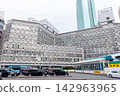 The view of Shinbashi Station Building No. 1 and the taxi stand: a retro Showa-era mixed-use building with towering skyscrapers in the background. 142963965