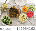 Freshly prepared potatoes, salads, and vegetables on a checkered tablecloth 142964162