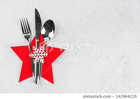 Christmas table setting with silver cutlery in red star shaped cutlery holder, background copy space Christmas table setting with silver cutlery in red star shaped cutlery holder, background copy space 142964220
