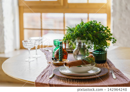Festive Christmas table setting with greenery candles and elegant tableware on window background Festive Christmas table setting with greenery candles and elegant tableware on window background 142964248