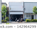 A local motorcycle shop and a moped scooter displayed in front of the shop. 142964299