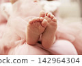 Close-up of cute newborn baby feet on a soft pink fabric background. 142964304