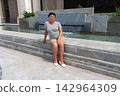 A woman is sitting on a stone staircase. 142964309