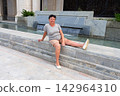 A woman is sitting on a stone staircase. 142964310