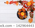 Seasonal banner featuring maple leaves, pine cones, nuts, pumpkins, and rowan berries, Thanksgiving themed still life or website header, an abstract autumn composition for a greeting card 142964443