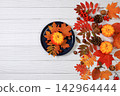 Abstract autumn composition with maple leaves, pine cones, nuts, pumpkins, and rowan berries; still life, Thanksgiving theme, seasonal background, website banner or header, greeting card 142964444