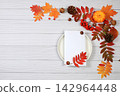 Abstract autumn composition with maple leaves, pine cones, nuts, pumpkins, and rowan berries; still life, Thanksgiving theme, seasonal background, website banner or header, greeting card 142964448