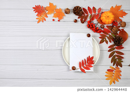 Abstract autumn composition with maple leaves, pine cones, nuts, pumpkins, and rowan berries; still life, Thanksgiving theme, seasonal background, website banner or header, greeting card 142964448