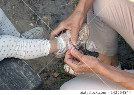Senior Woman Helping Child Adjust Casual Shoe 142964544