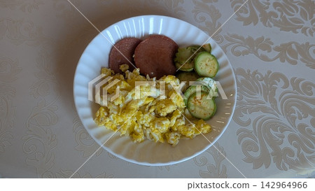 Homemade breakfast with scrambled eggs sliced sausage and zucchini served on a white plate Homemade breakfast with scrambled eggs sliced sausage and zucchini served on a white plate 142964966