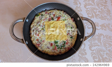 Homemade vegetable frittata with a slice of melted cheese in a frying pan Homemade vegetable frittata with a slice of melted cheese in a frying pan 142964969