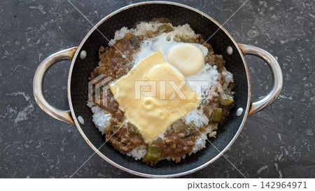 Homemade curry rice topped with a fried egg and melted cheese inside a pan Homemade curry rice topped with a fried egg and melted cheese inside a pan 142964971
