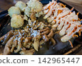 Detailed macro close up of Japanese style chicken teriyaki with sesame seeds, fresh carrot salad with mayo, and fried side dishes on a dark plate. 142965447