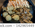 Detailed macro close up of Japanese style chicken teriyaki with sesame seeds, fresh carrot salad with mayo, and fried side dishes on a dark plate. 142965449