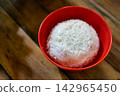Freshly cooked white steamed rice served in a red bowl on a wooden table, traditional Asian staple food and side dish for set meals. 142965450