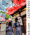 姊妹倆抬頭望向小樽市首前廣場上裝飾著日式雨傘的街景。 142965460